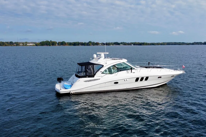  Yacht Photos Pics 2009 Sea Ray 48 Sundancer yacht cruising on a calm lake under a partly cloudy sky.