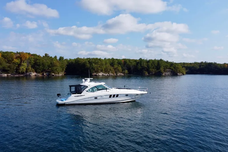  Yacht Photos Pics 2009 Sea Ray 48 Sundancer yacht cruising on a serene lake with forested shoreline.