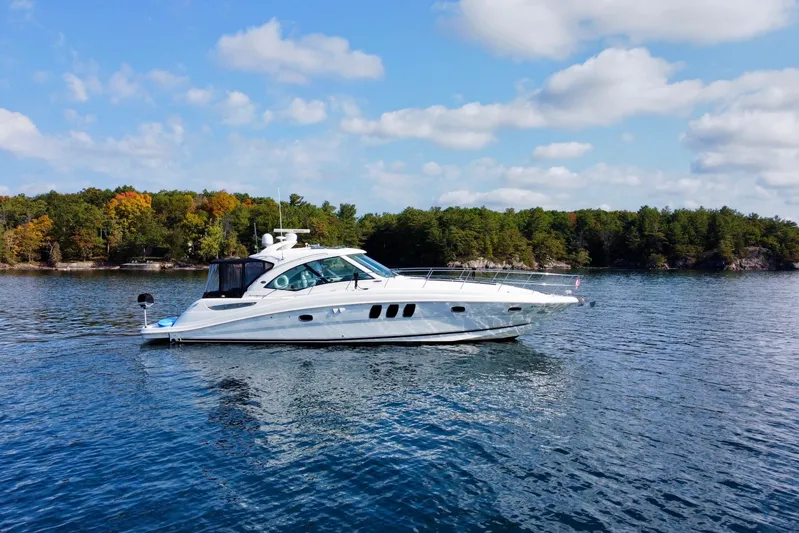  Yacht Photos Pics 2009 Sea Ray 48 Sundancer yacht cruising on a serene lake with forested shoreline.