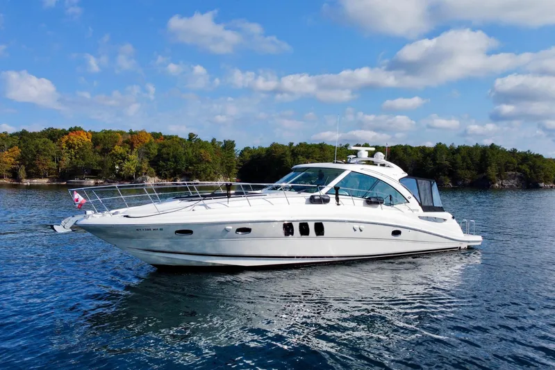  Yacht Photos Pics 2009 Sea Ray 48 Sundancer yacht on a serene lake with forested shoreline.