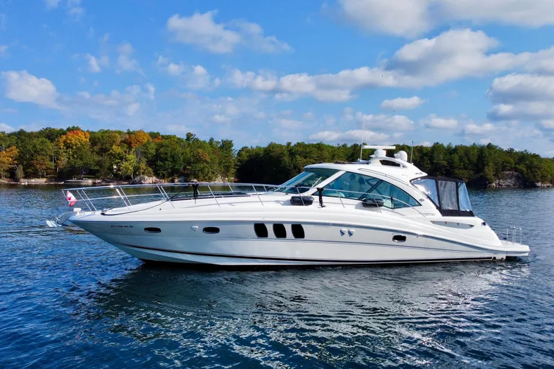  Yacht Photos Pics 2009 Sea Ray 48 Sundancer yacht cruising on a serene lake with lush forest backdrop.