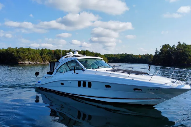  Yacht Photos Pics 2009 Sea Ray 48 Sundancer yacht cruising on a serene lake with lush green shoreline.