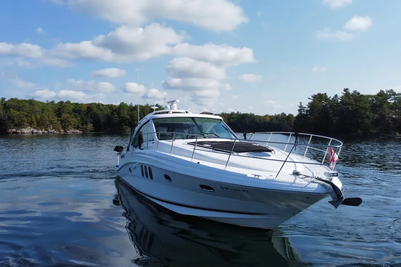  Yacht Photos Pics 2009 Sea Ray 48 Sundancer yacht cruising on a serene lake with forested shoreline.