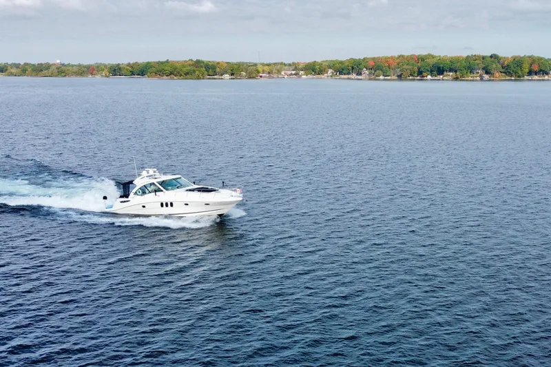  Yacht Photos Pics 2009 Sea Ray 48 Sundancer cruising on a serene lake with a forested shoreline.