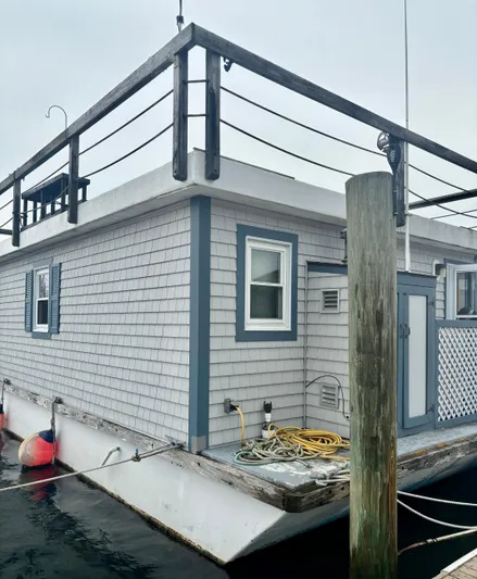  Yacht Photos Pics Custom 1990 houseboat with gray siding and blue trim, docked with nautical equipment.
