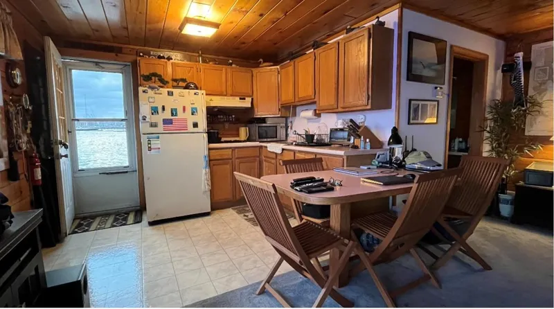  Yacht Photos Pics Cozy houseboat kitchen with wooden cabinets, dining table, and lake view. Custom model, 1990.