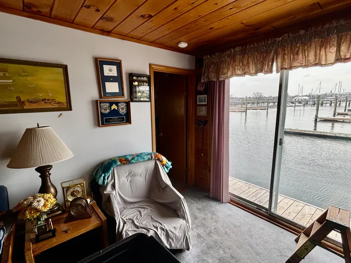  Yacht Photos Pics Cozy houseboat interior with chair, lamp, and marina view through sliding glass door.