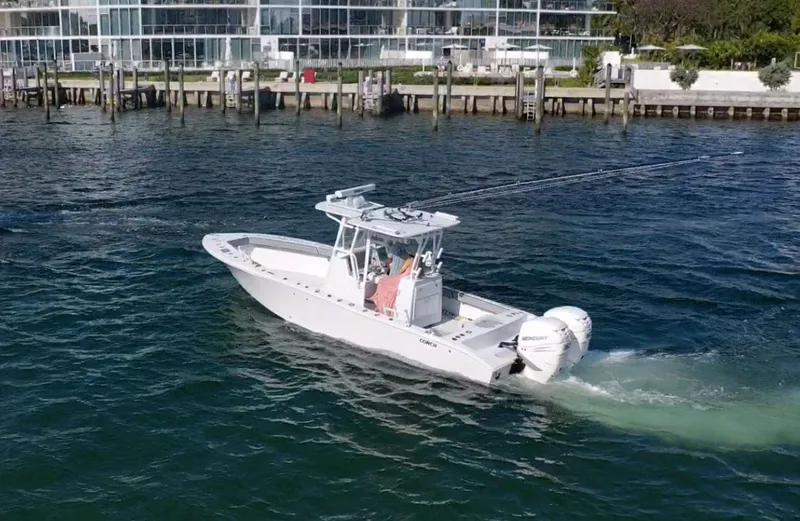 Pamela Ann Yacht Photos Pics 2018 Conch 30 boat cruising on water near a modern waterfront building.