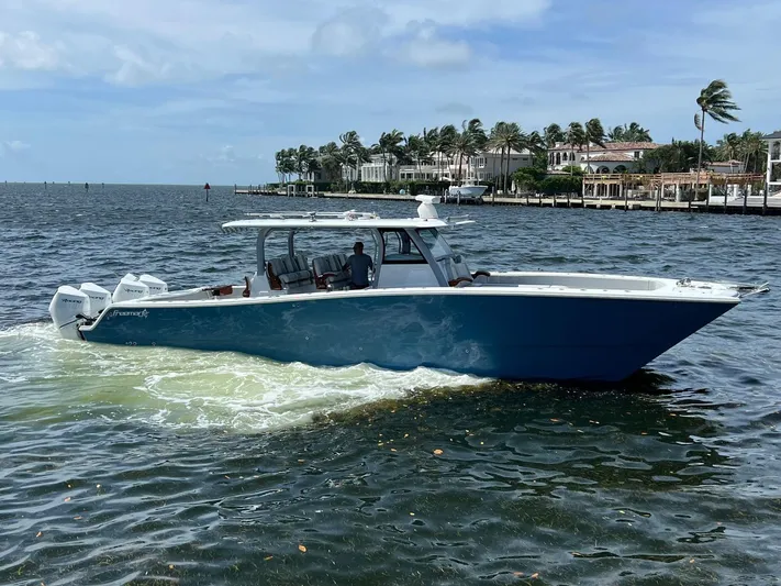 Nomad Yacht Photos Pics 2021 Freeman 42 LR boat cruising on a sunny day near waterfront homes.