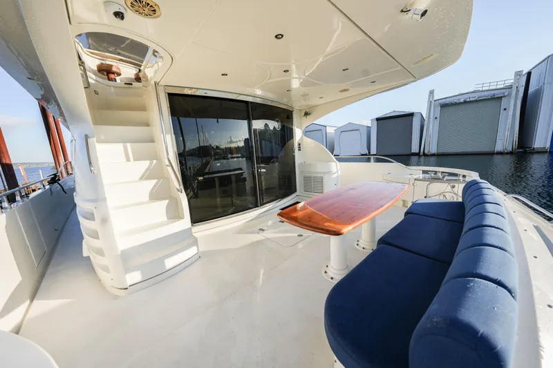  Yacht Photos Pics Luxurious 2006 Marquis 65 yacht deck with blue seating, wooden table, and spiral staircase.