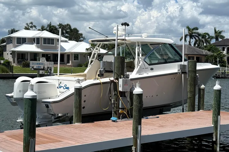  Yacht Photos Pics 2016 Pursuit DC 325 Dual Console boat docked by waterfront homes under cloudy sky.