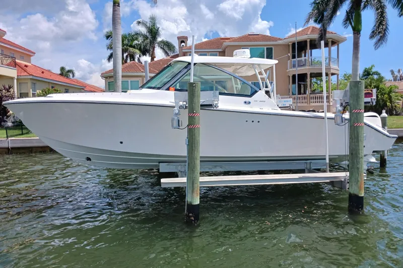  Yacht Photos Pics 2016 Pursuit DC 325 Dual Console boat on lift, waterfront homes in background.