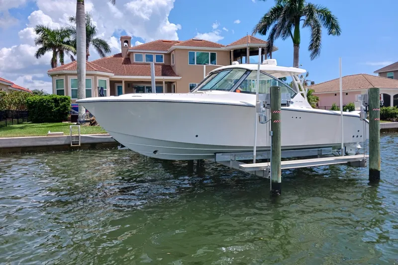  Yacht Photos Pics 2016 Pursuit DC 325 Dual Console boat on lift near waterfront home.