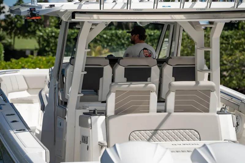 Nomad Yacht Photos Pics 2022 Pursuit S 428 Sport boat with a person at the helm, featuring modern seating.