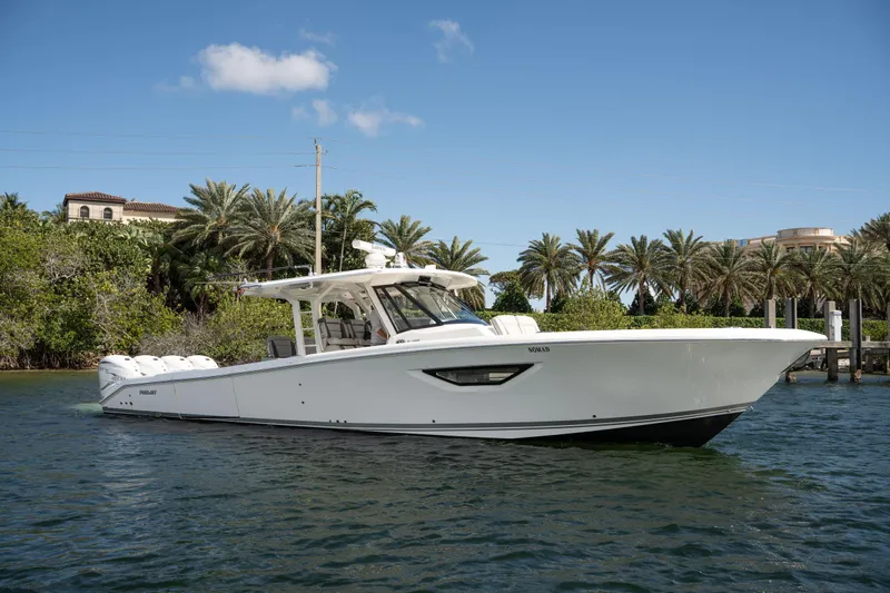 Nomad Yacht Photos Pics 2022 Pursuit S 428 Sport boat on water, surrounded by palm trees and clear sky.