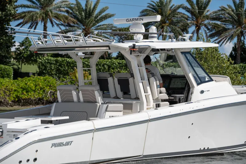 Nomad Yacht Photos Pics 2022 Pursuit S 428 Sport boat cruising near palm trees.