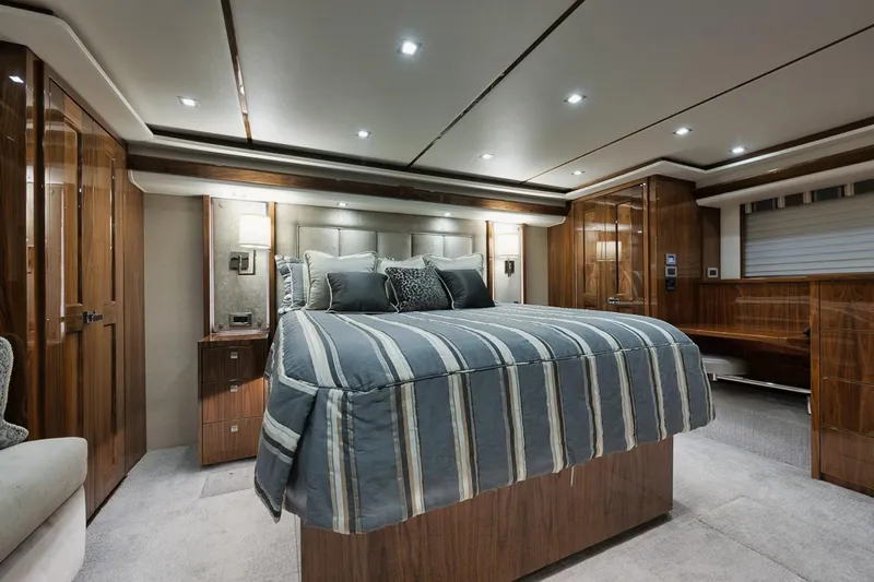  Yacht Photos Pics Luxurious bedroom interior of 2019 Viking 80 Convertible yacht with elegant wood finishes.