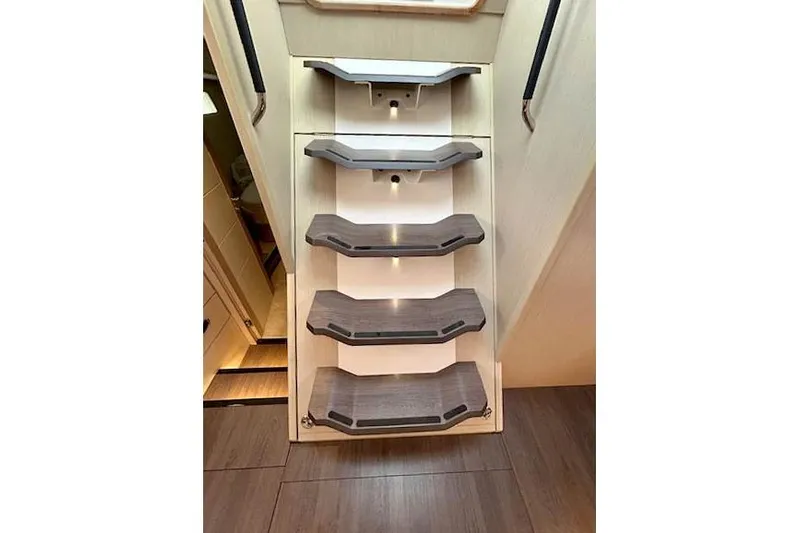 Chase'n Grace Yacht Photos Pics Modern staircase inside 2022 Jeanneau Yachts 60, featuring sleek wooden steps and ambient lighting.