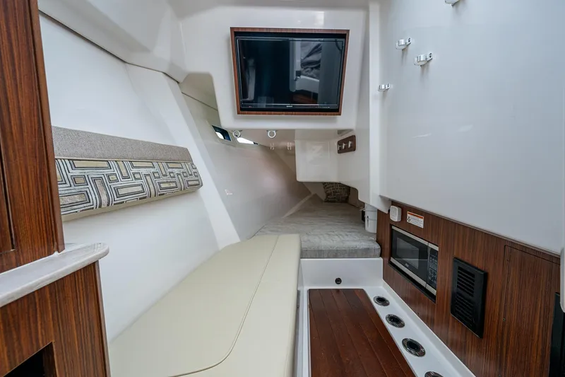  Yacht Photos Pics 2023 Pursuit DC 365 Dual Console interior with TV, seating, and wood accents.
