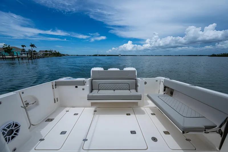  Yacht Photos Pics 2023 Pursuit DC 365 Dual Console boat interior with seating, overlooking calm waters and blue sky.