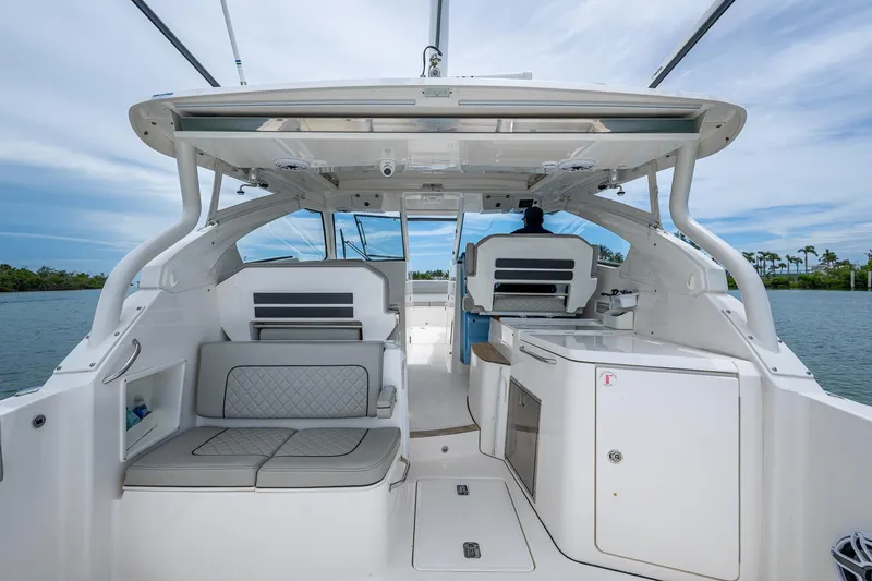  Yacht Photos Pics 2023 Pursuit DC 365 Dual Console boat interior with seating and helm, on a calm waterway.