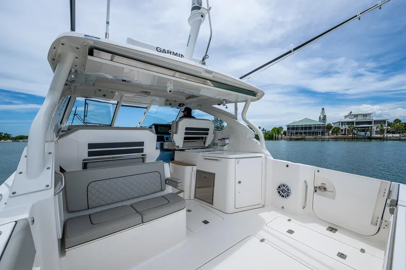  Yacht Photos Pics 2023 Pursuit DC 365 Dual Console boat interior with seating and helm, docked by waterfront homes.