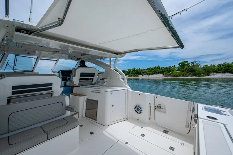  Yacht Photos Pics 2023 Pursuit DC 365 Dual Console boat interior with seating, canopy, and water view.