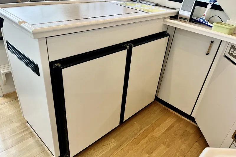  Yacht Photos Pics Kitchen area of a 1996 Bayliner 3988 Motoryacht with white cabinetry and wood flooring.