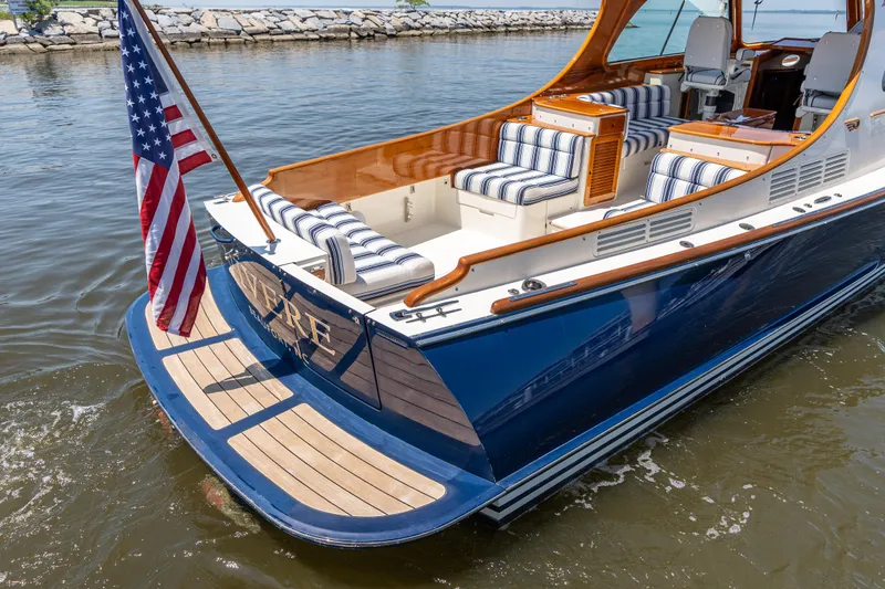 Vivere Yacht Photos Pics 2015 Hinckley Picnic Boat 37 MKIII with striped seating and American flag on water.