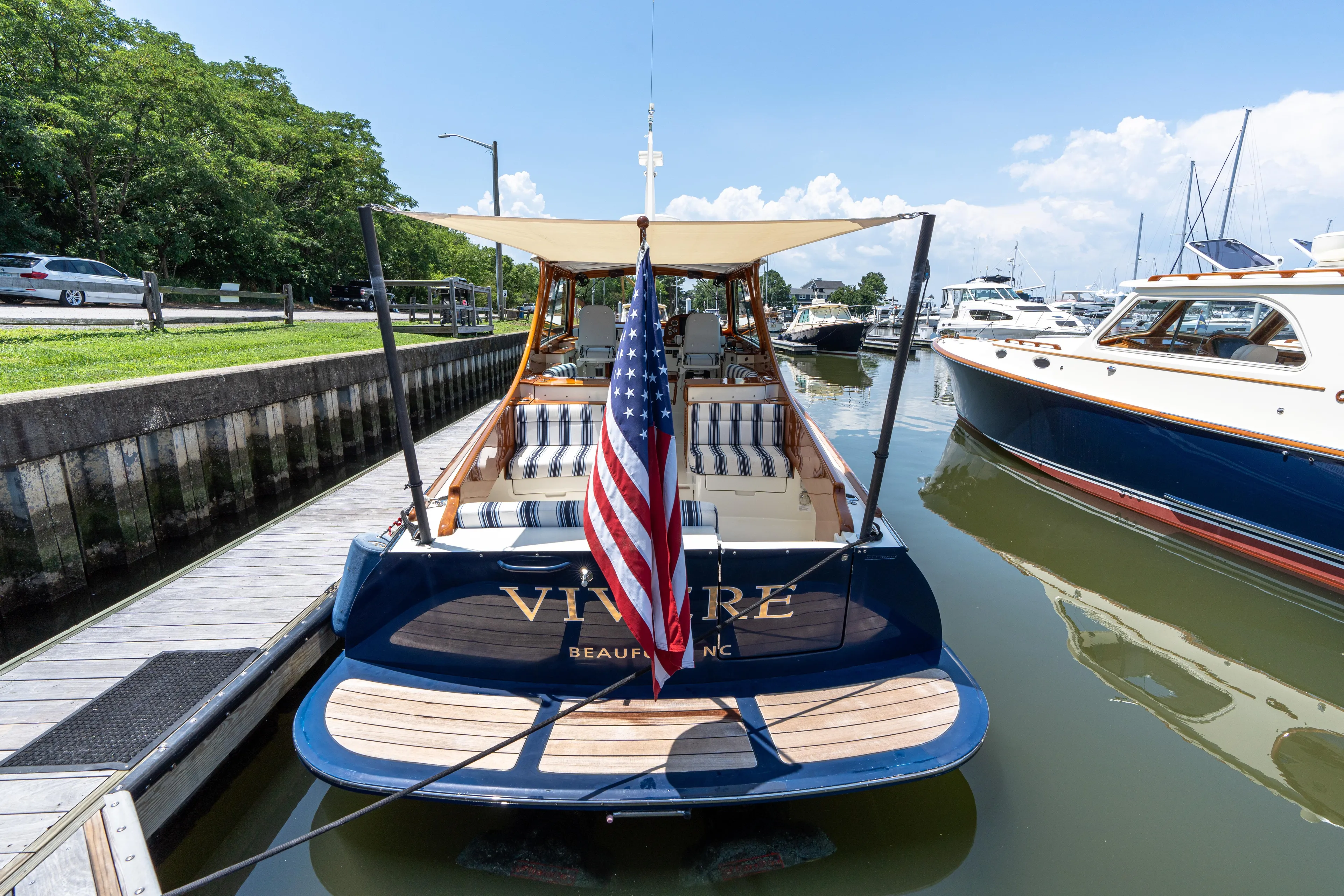 Vivere Yacht Photos Pics 2015 Hinckley Picnic Boat 37 MKIII docked with American flag, striped seating, and canopy.