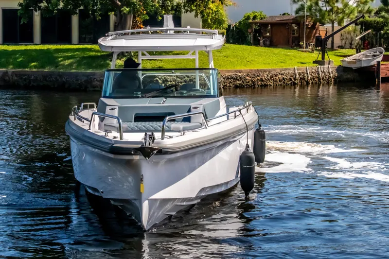  Yacht Photos Pics 2024 Axopar 37 Sun Top cruising on a calm river, surrounded by greenery.