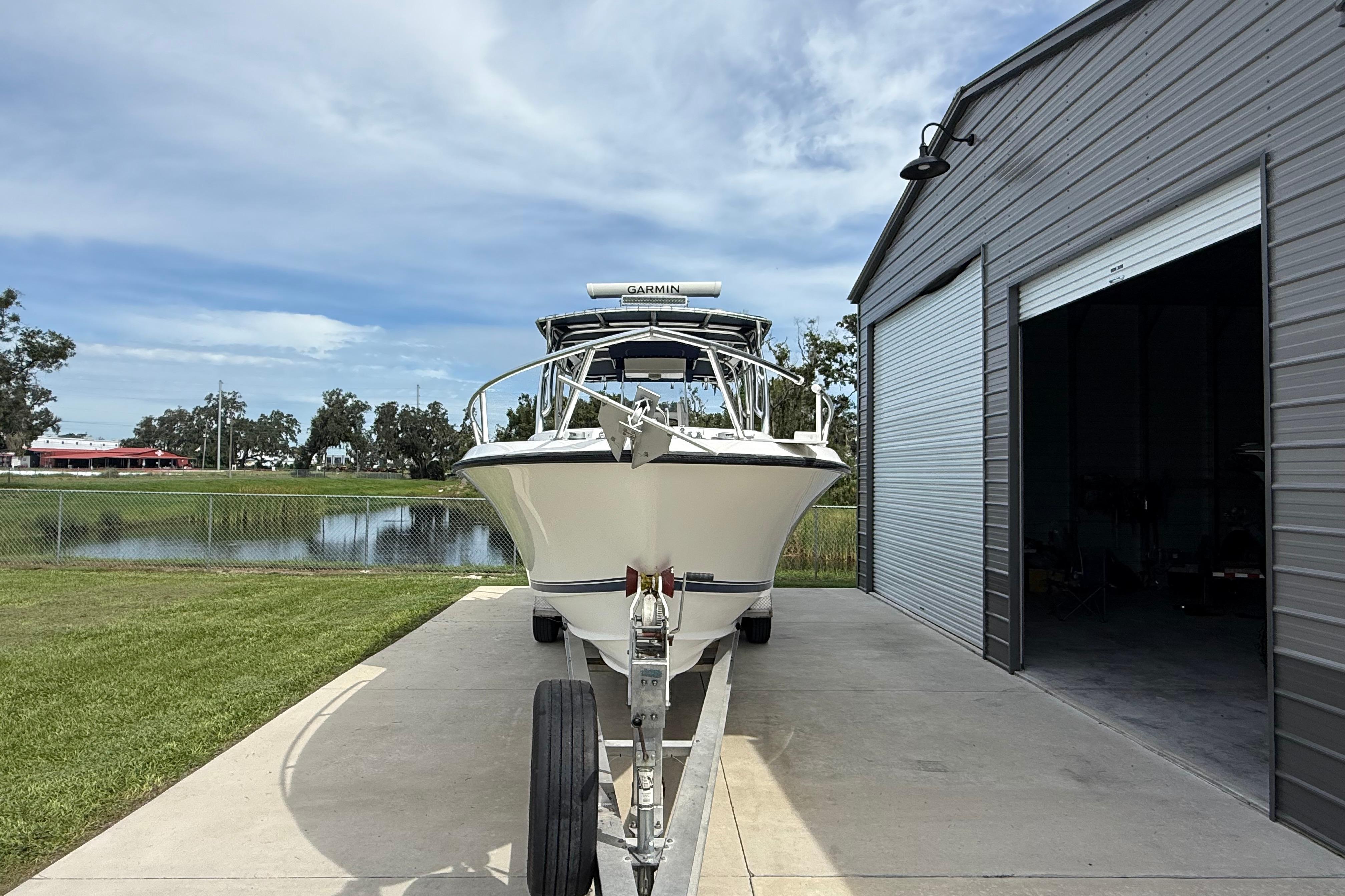 2008 Contender 31 Cuddy boat on trailer near metal building and pond.