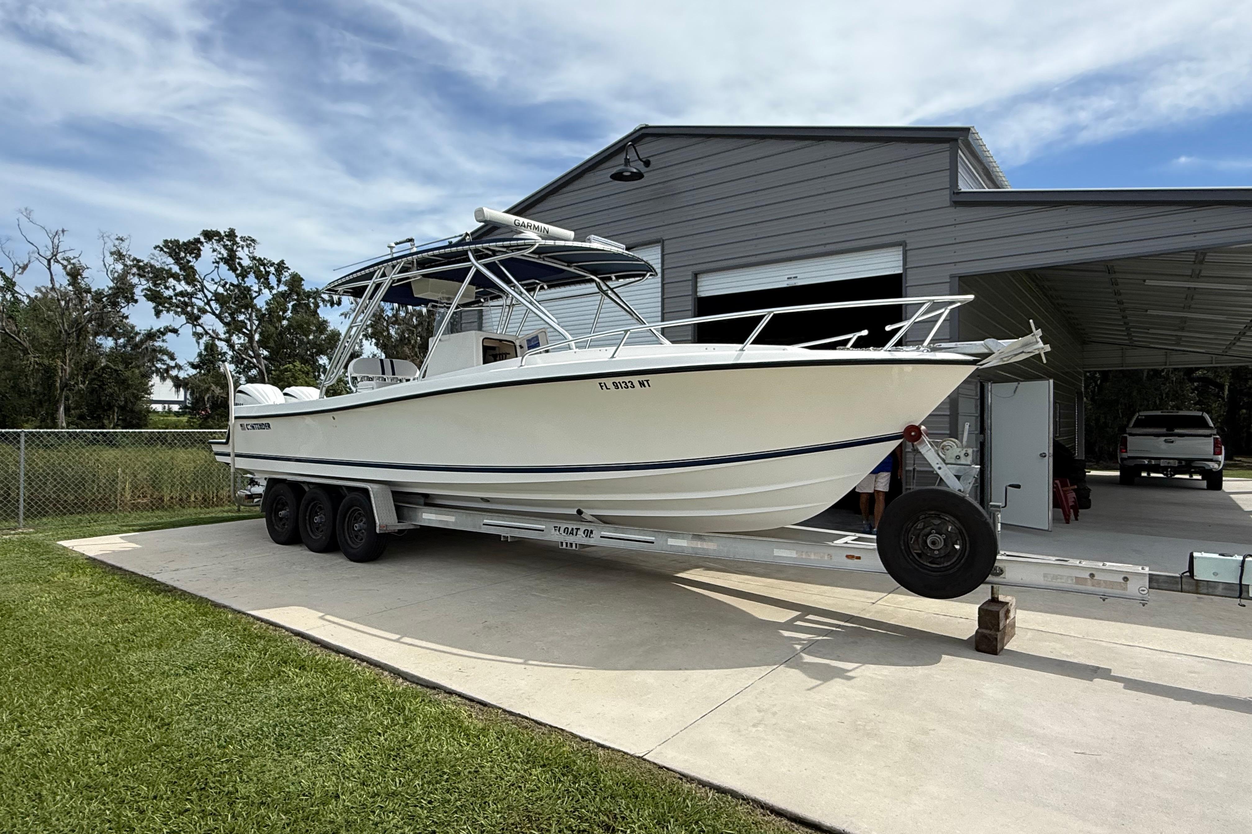 2008 Contender 31 Cuddy boat on trailer, parked outside a garage.