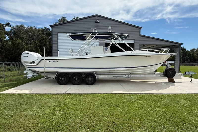  Yacht Photos Pics 2008 Contender 31 Cuddy boat on trailer, parked outside a large garage.