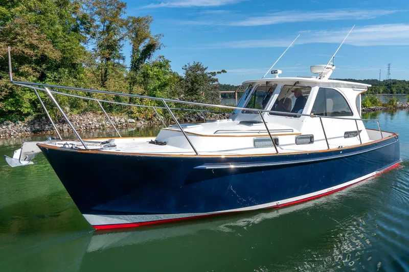  Yacht Photos Pics 2002 Legacy 34 Express boat cruising on a serene lake under a clear blue sky.