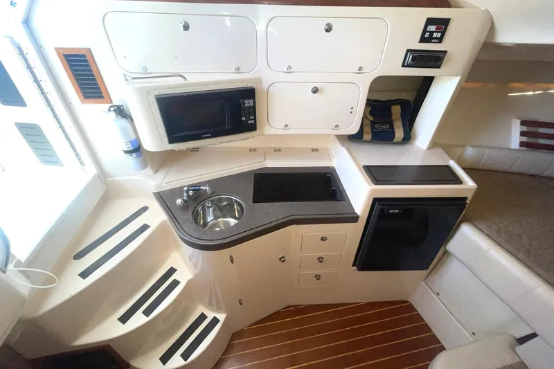  Yacht Photos Pics 2003 Grady-White Express 330 cabin with kitchenette, featuring sink, microwave, and compact fridge.