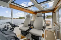 Interior of 2021 Nimbus C11 boat with dual captain chairs and panoramic windows.