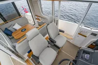 Interior of 2021 Nimbus C11 boat with seating, table, and helm, overlooking water.