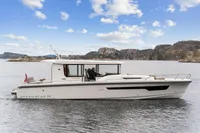 Nimbus C11 2021 boat cruising on a scenic lake with rocky hills in the background.