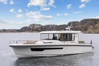 Nimbus C11 2021 boat cruising on a scenic lake with rocky hills in the background.