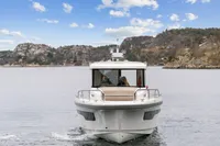 2021 Nimbus C11 boat cruising on a scenic lake with rocky hills in the background.