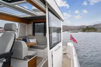 Modern Nimbus C11 boat interior with scenic lake view, featuring comfortable seating and Norwegian flag.