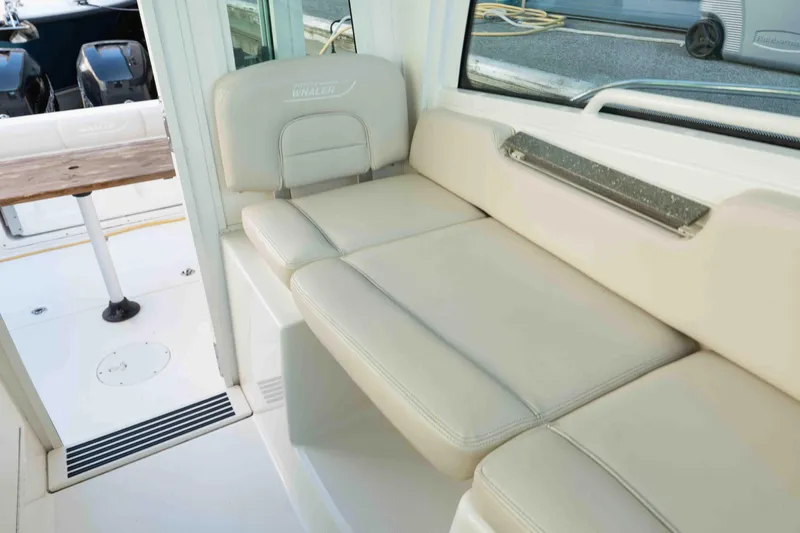  Yacht Photos Pics 2016 Boston Whaler 285 Conquest Pilothouse interior with beige seating and outdoor view.