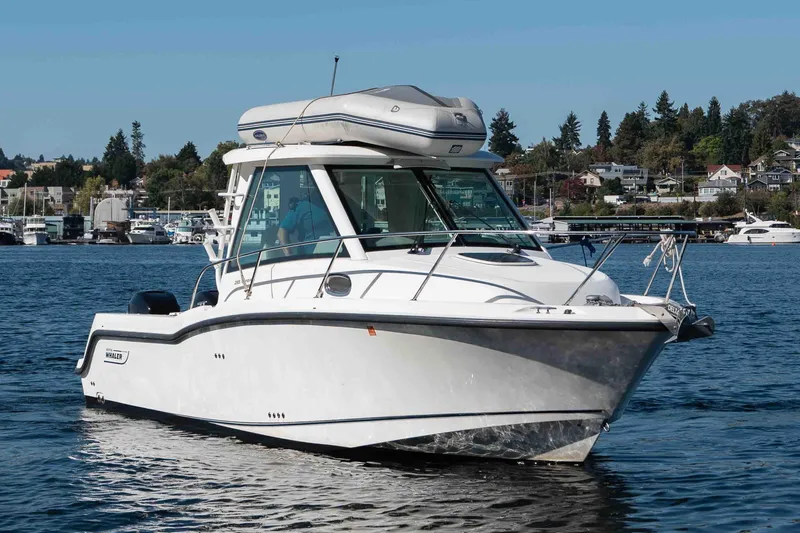  Yacht Photos Pics 2016 Boston Whaler 285 Conquest Pilothouse boat on calm water, with scenic background.