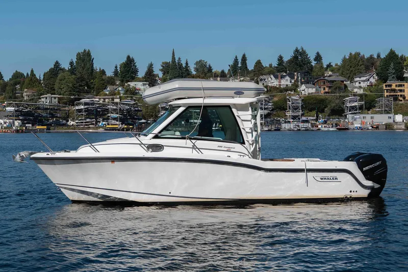 Yacht Photos Pics 2016 Boston Whaler 285 Conquest Pilothouse boat on calm water, with scenic shoreline background.