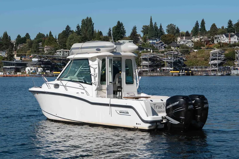  Yacht Photos Pics 2016 Boston Whaler 285 Conquest Pilothouse on calm water, surrounded by scenic shoreline.