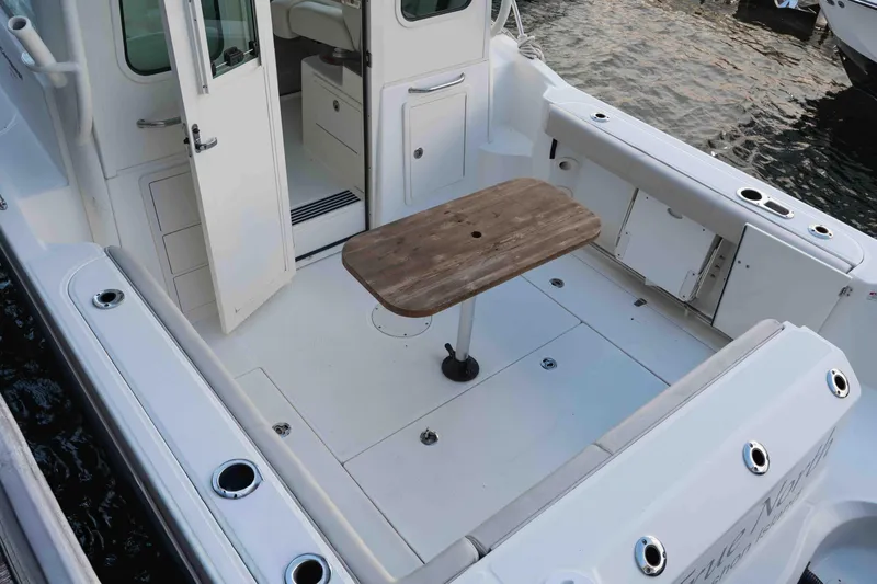  Yacht Photos Pics 2016 Boston Whaler 285 Conquest Pilothouse boat interior with wooden table and open door.