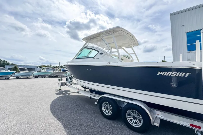  Yacht Photos Pics 2023 Pursuit DC 266 Dual Console boat on trailer under cloudy sky.