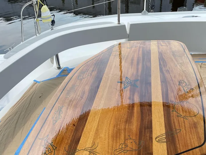  Yacht Photos Pics Polished wooden table on 2006 Fountaine Pajot LAVEZZI catamaran deck, featuring nautical engravings.