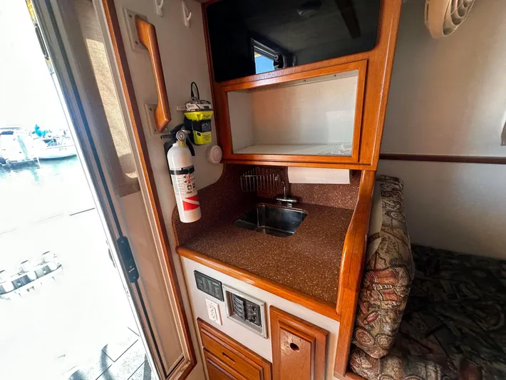 Firefly Yacht Photos Pics Compact kitchen area in a 2008 Davis Rock Harbor boat with sink and fire extinguisher.